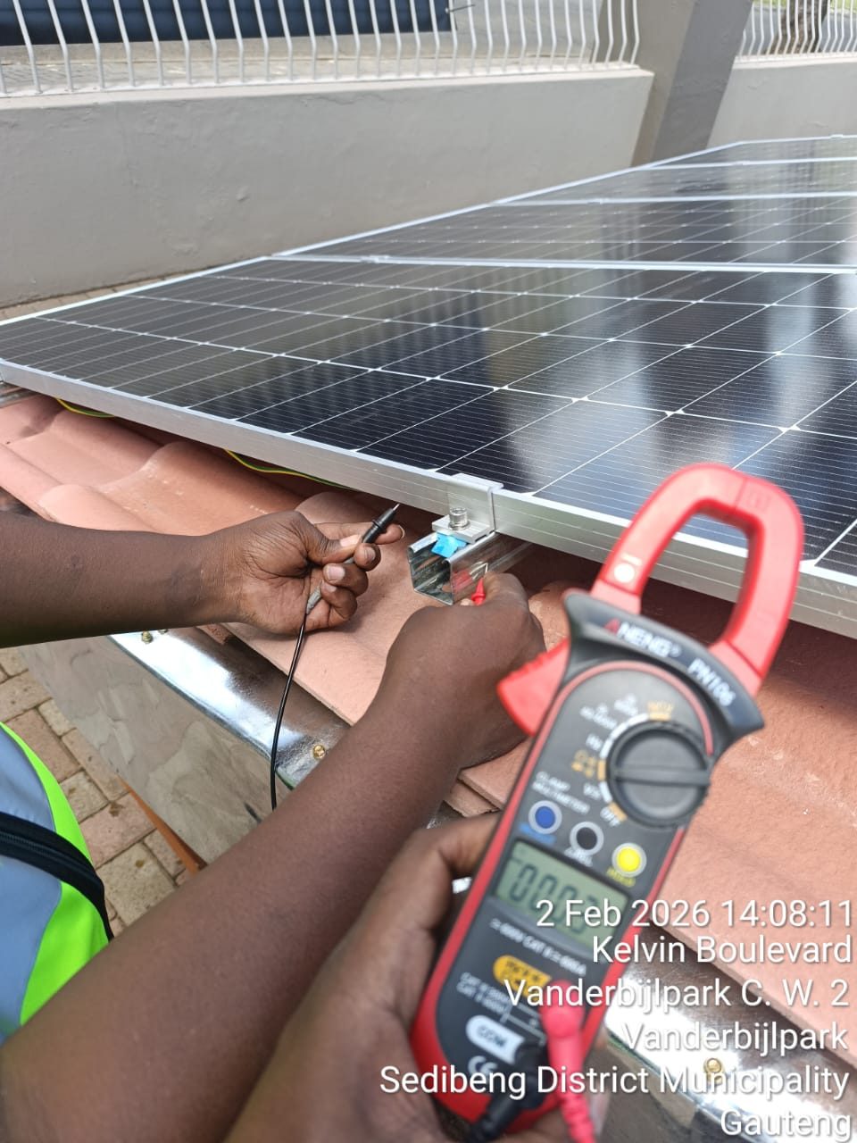 Busara trainee testing a solar PV installation with a clamp multimeter