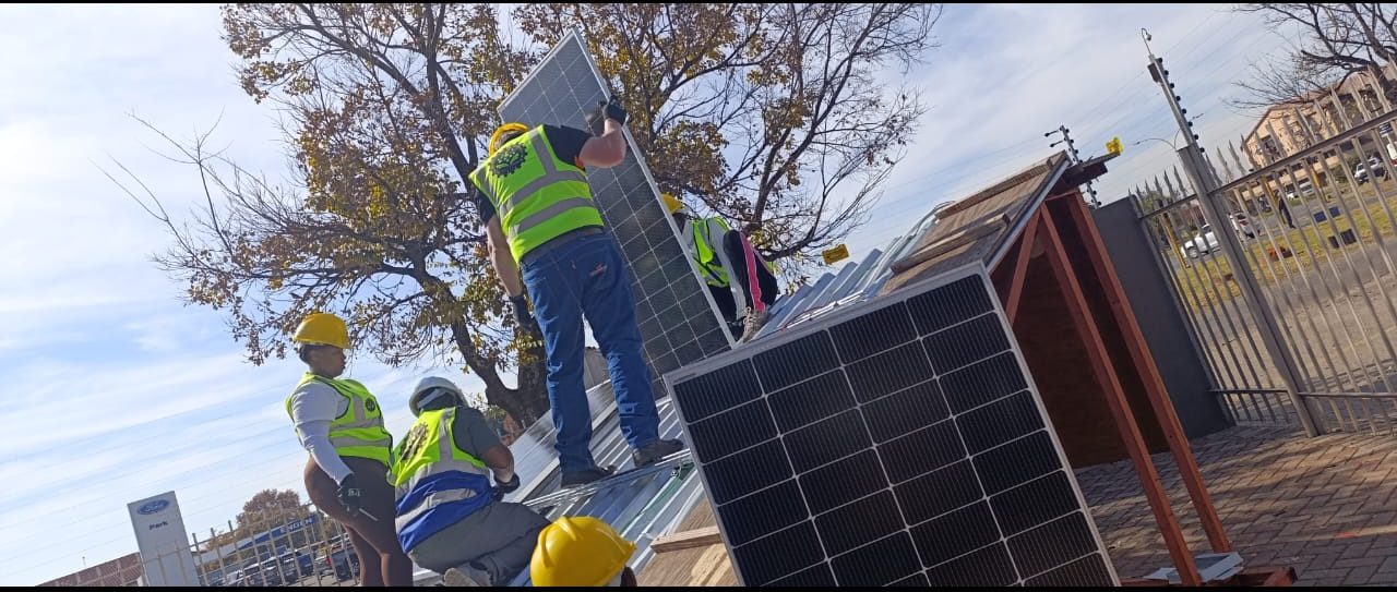 Trainees carrying a solar panel onto the training roof