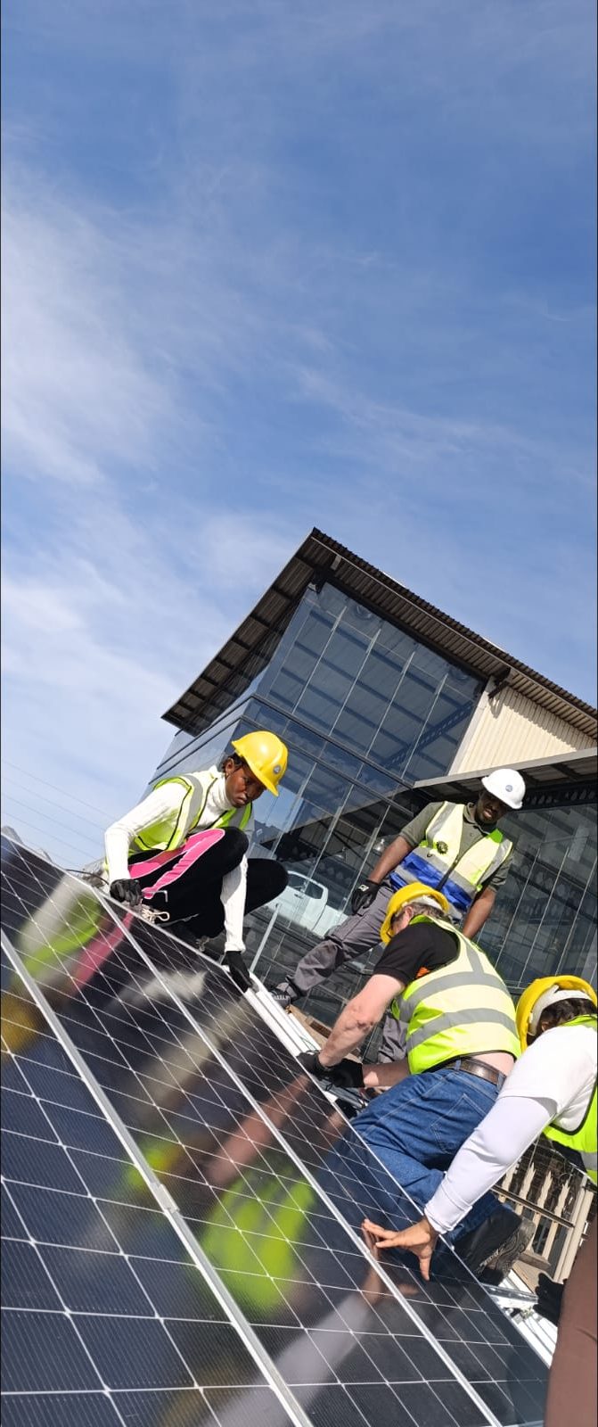 Trainees securing solar panels on the training roof