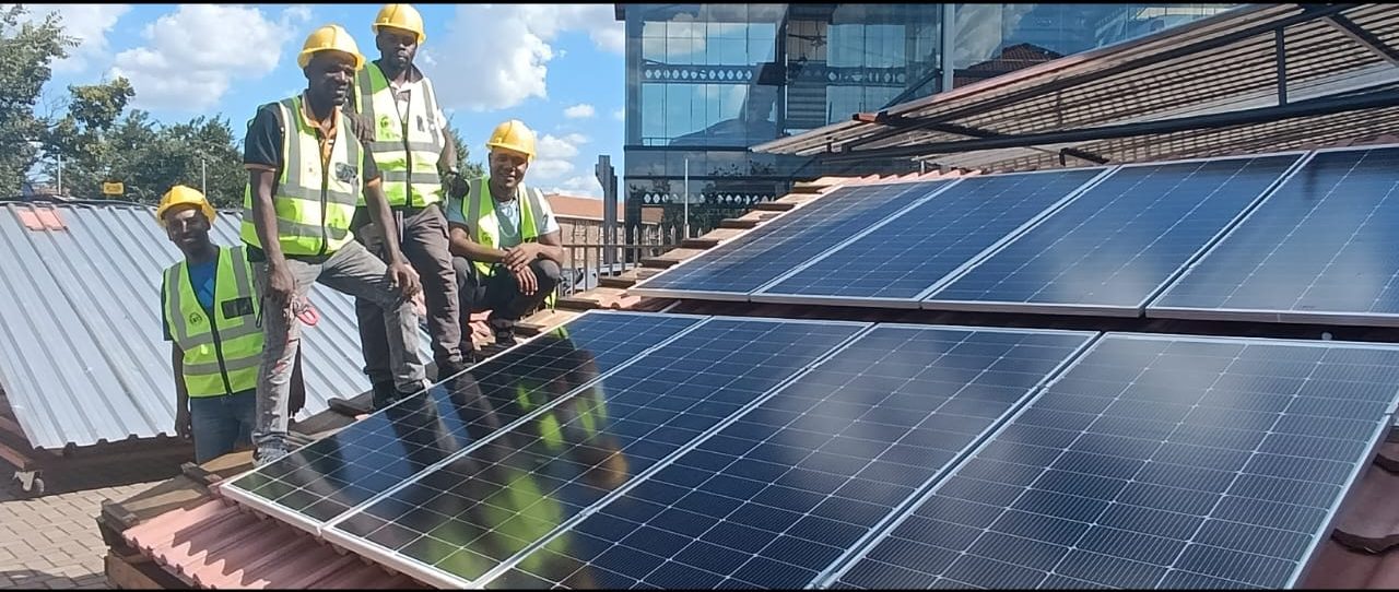 Trainees on a training roof beside a completed solar panel installation